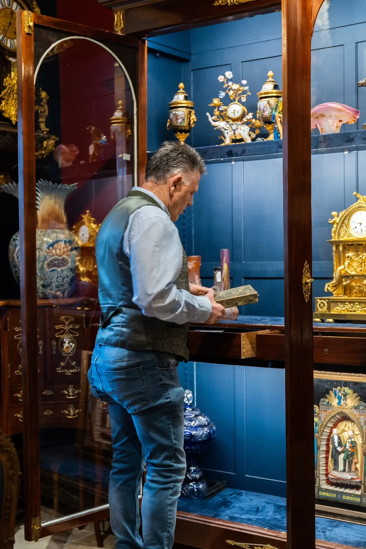 Marc De Leener range un livre antique précieux dans la vitrine de sa galerie d'art.