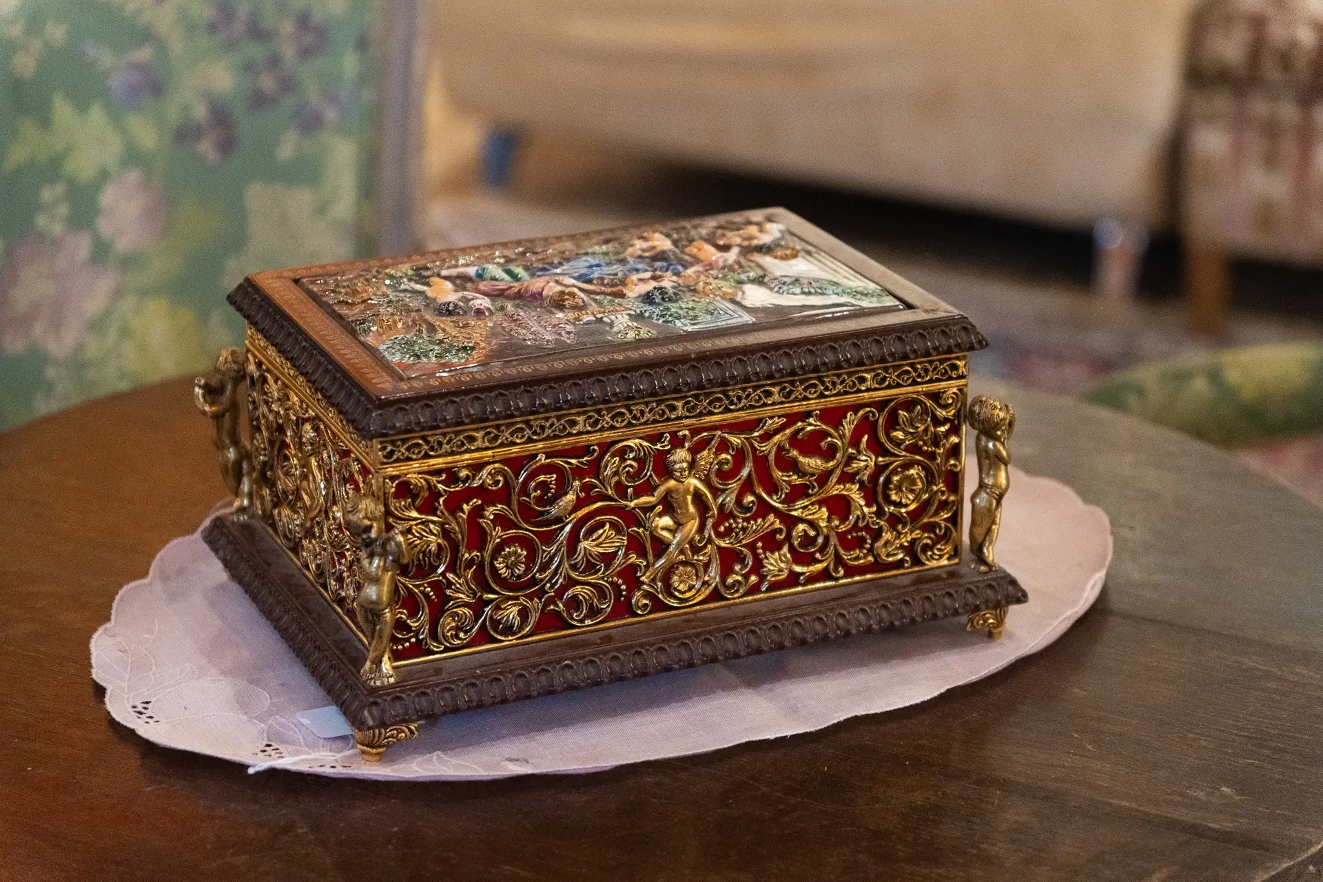 Coffret ancien richement décoré avec des détails dorés et un couvercle orné d'une scène artistique.